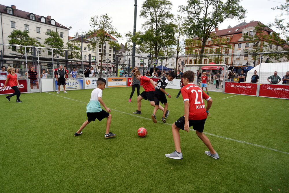 Kinder im Trikot spielen auf Kunstrasen Fußball