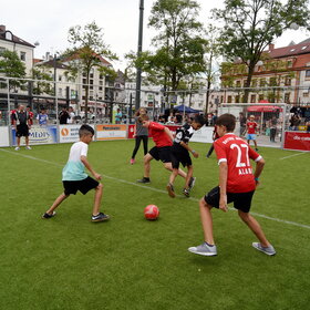 Kinder im Trikot spielen auf Kunstrasen Fußball