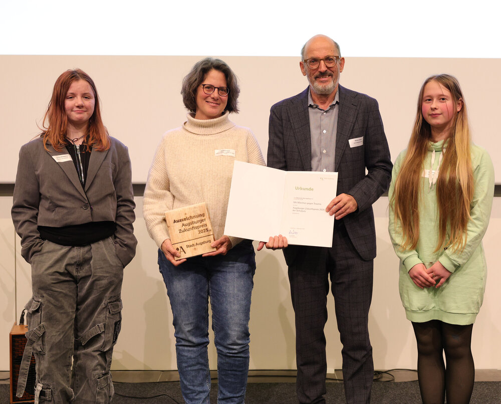 Gruppenbild von 4 menschen, die eine Urkunde halten
