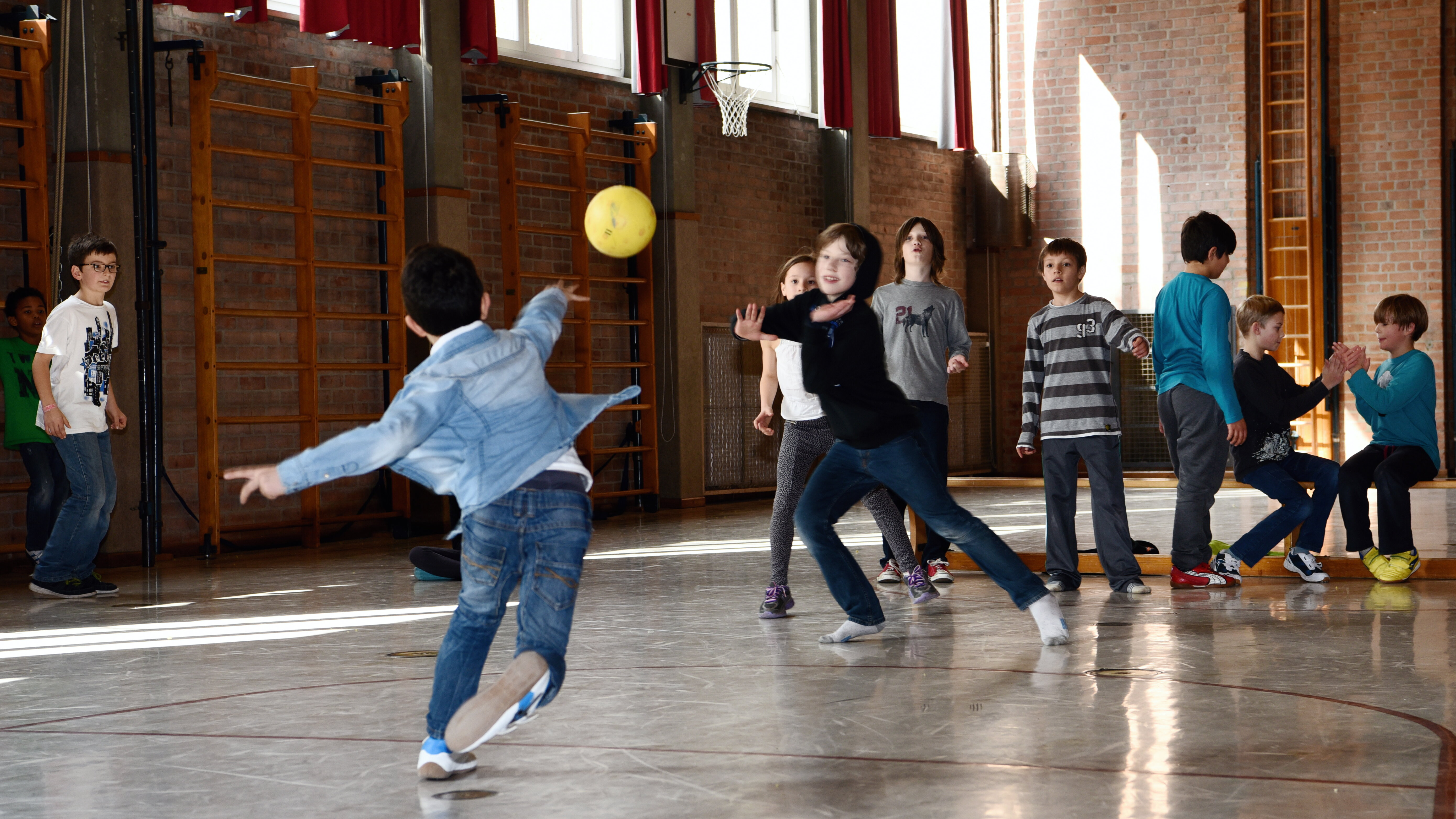 Kinder in Turnhalle werfen Ball