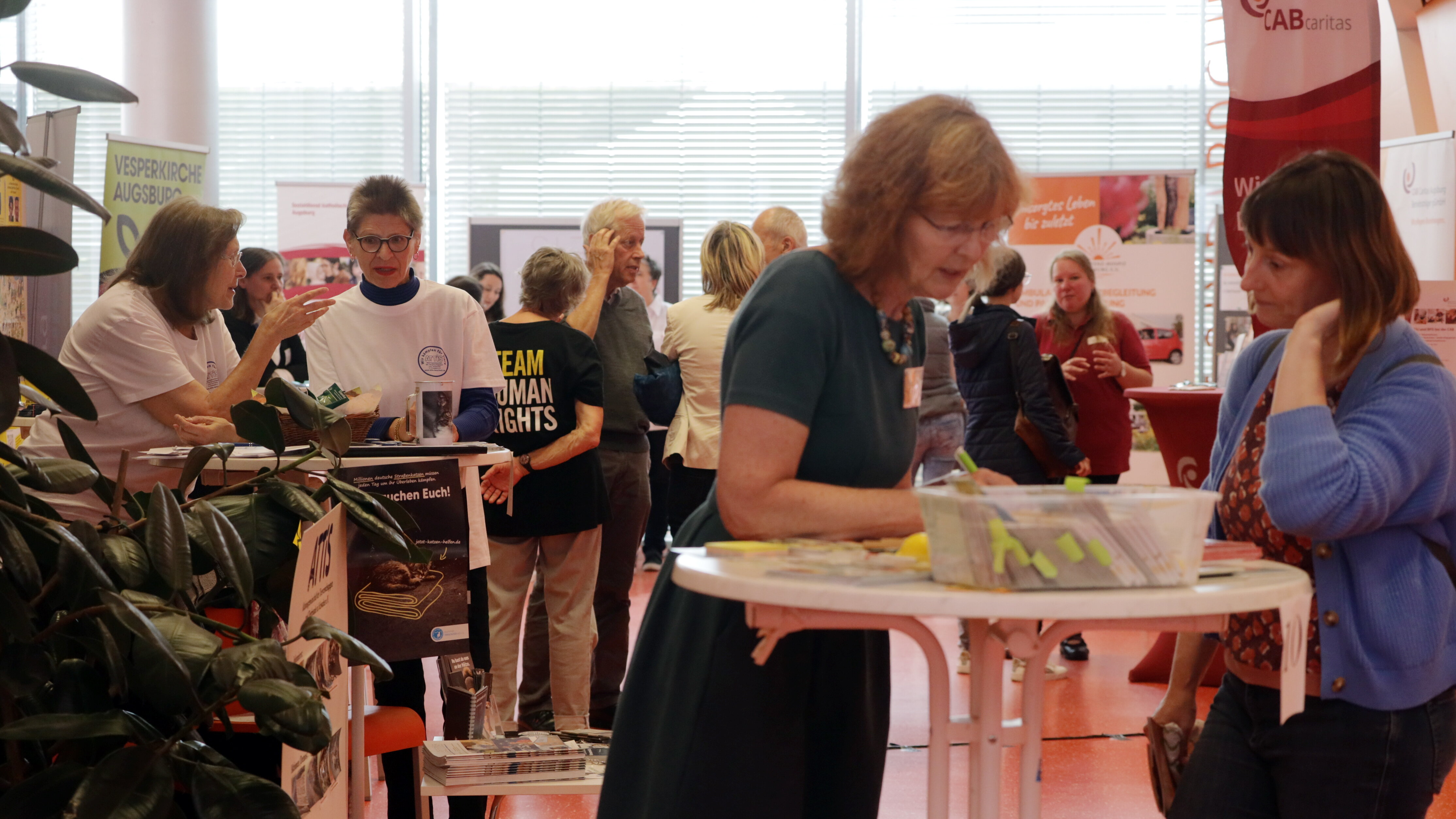 ein großer Raum, in dem verschiedene Rollups und Stehtische stehen, daran Menschen, die miteinander im Gespräch sind