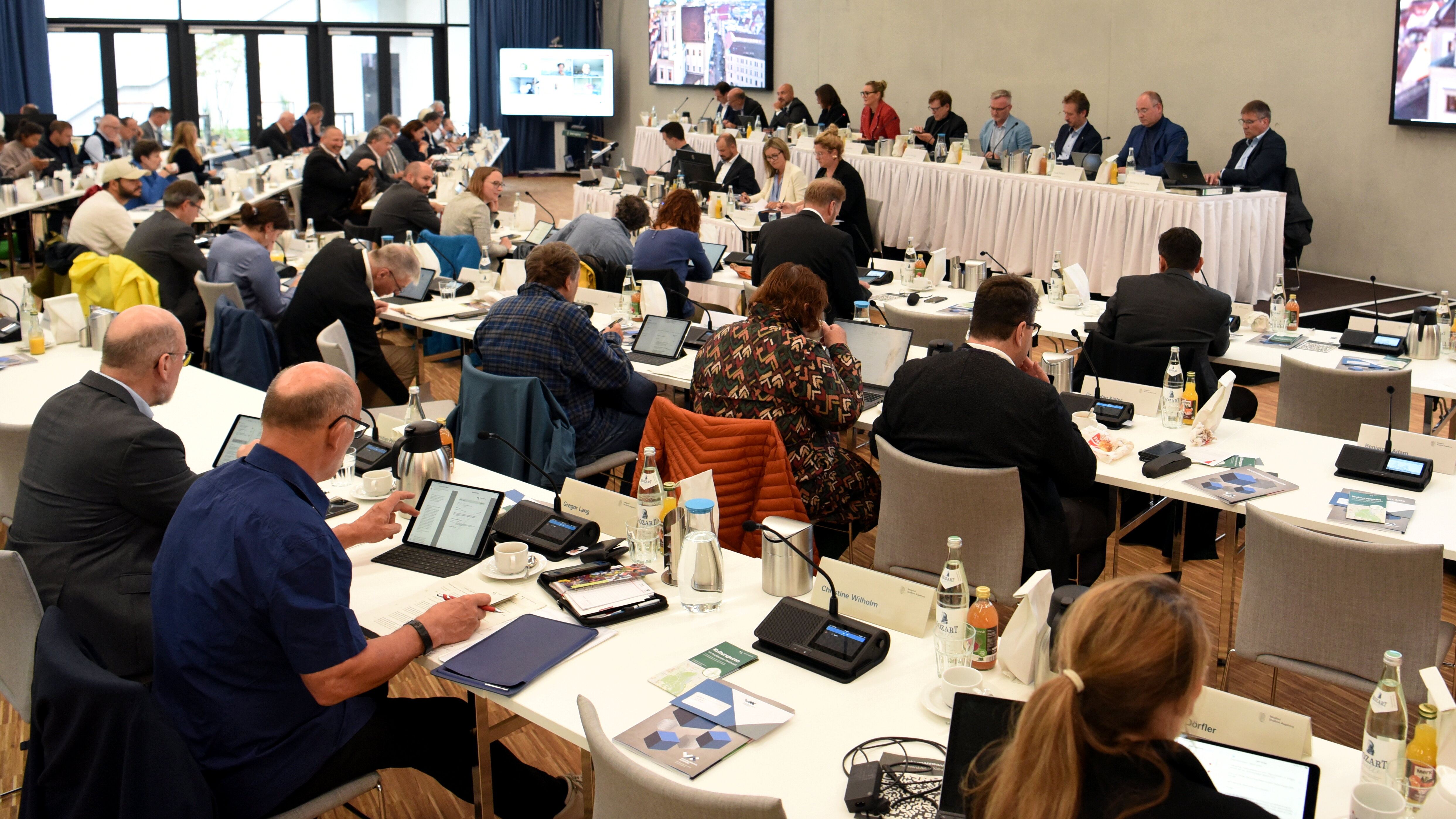 Der Stadtrat sitzt an langen Tischen in einem Sitzungssaal