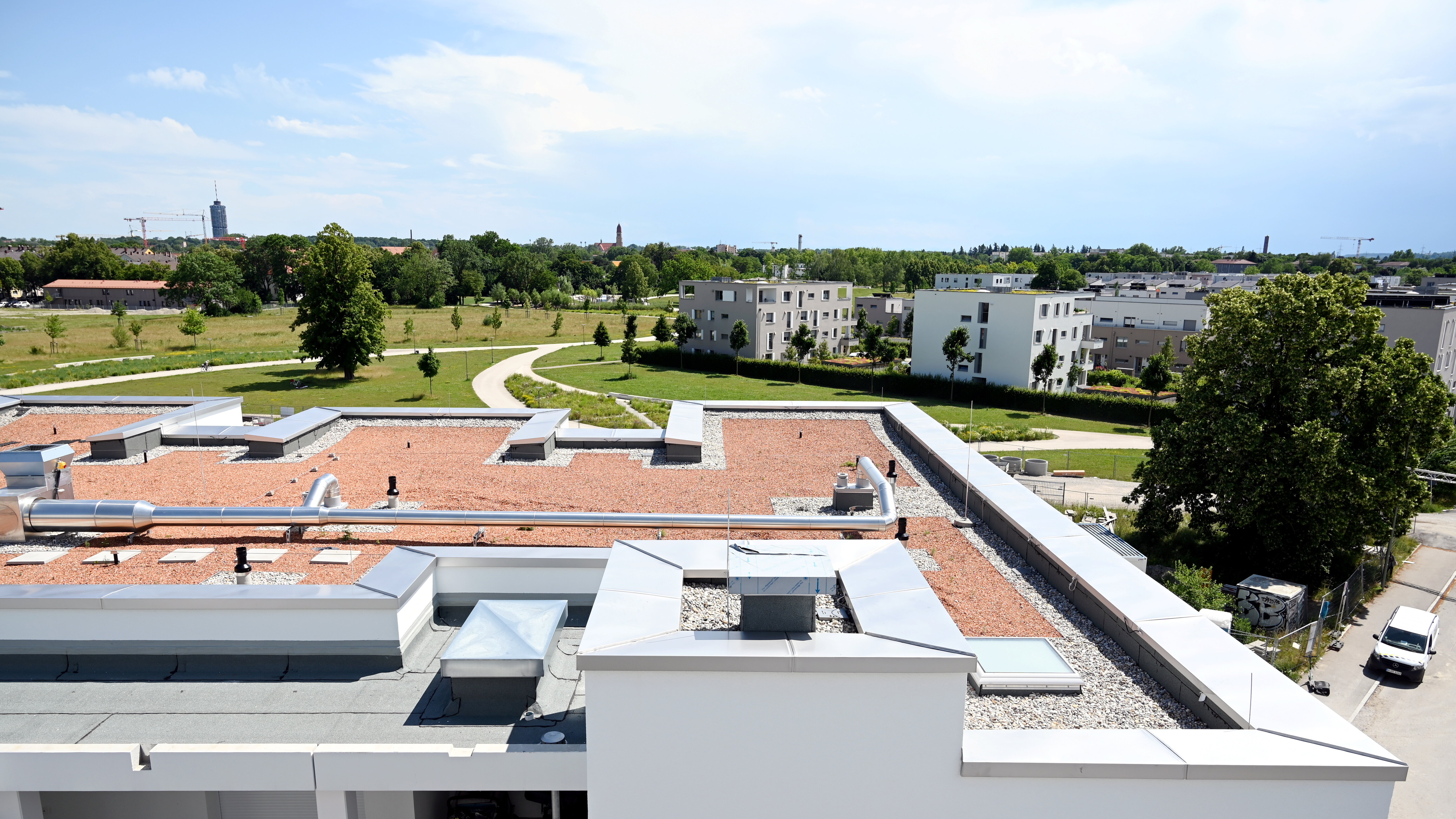 Blick über ein flaches Hausdach auf einen Park