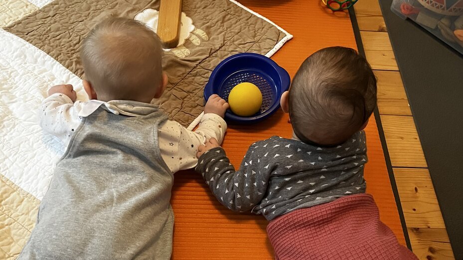 Zwei Babies krabbeln auf einer Decke und spielen