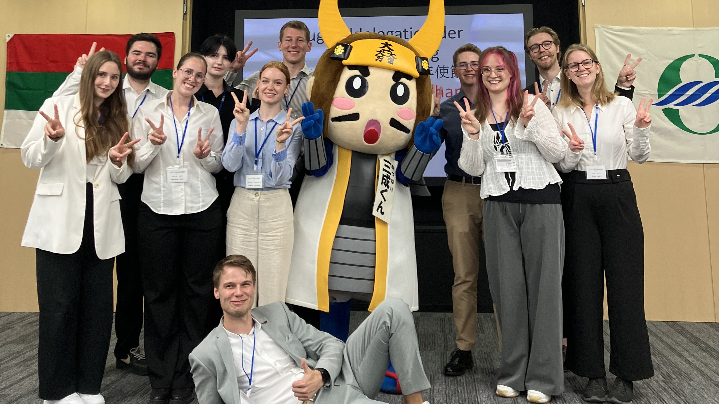 Etwa 12 junge Menschen stehen um eine japanische lebensgroße Manga-Figur