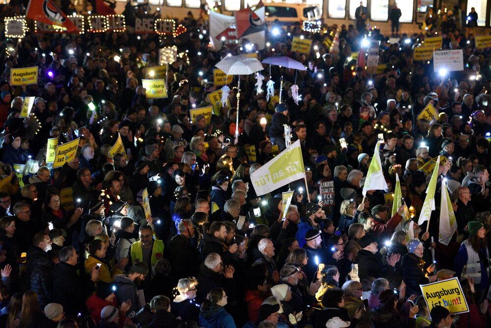 Auf dem Rathausplatz stehen mehrere Tausend Menschen bei Dunkelheit und halten Lichter in die Höhe