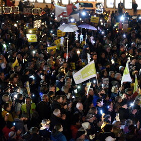 Auf dem Rathausplatz stehen mehrere Tausend Menschen bei Dunkelheit und halten Lichter in die Höhe