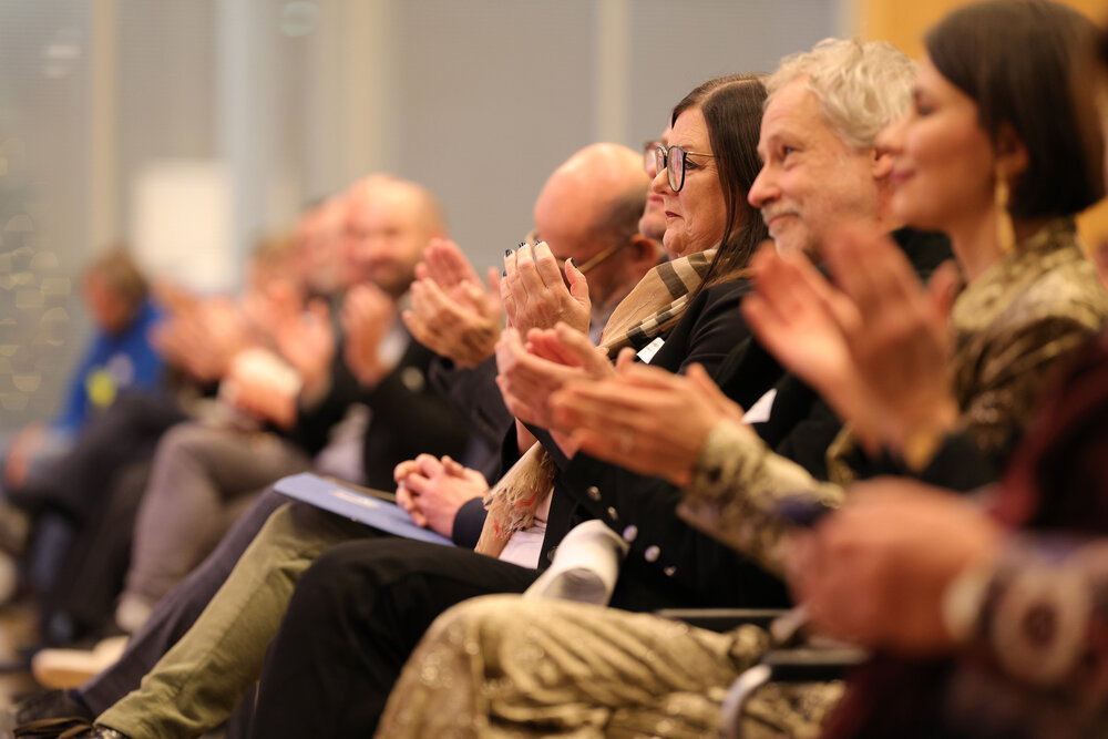 Menschen in der ersten Stuhlreihe klatschen