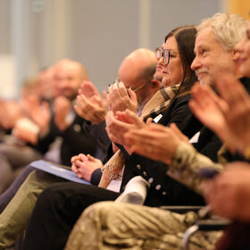 Menschen in der ersten Stuhlreihe klatschen
