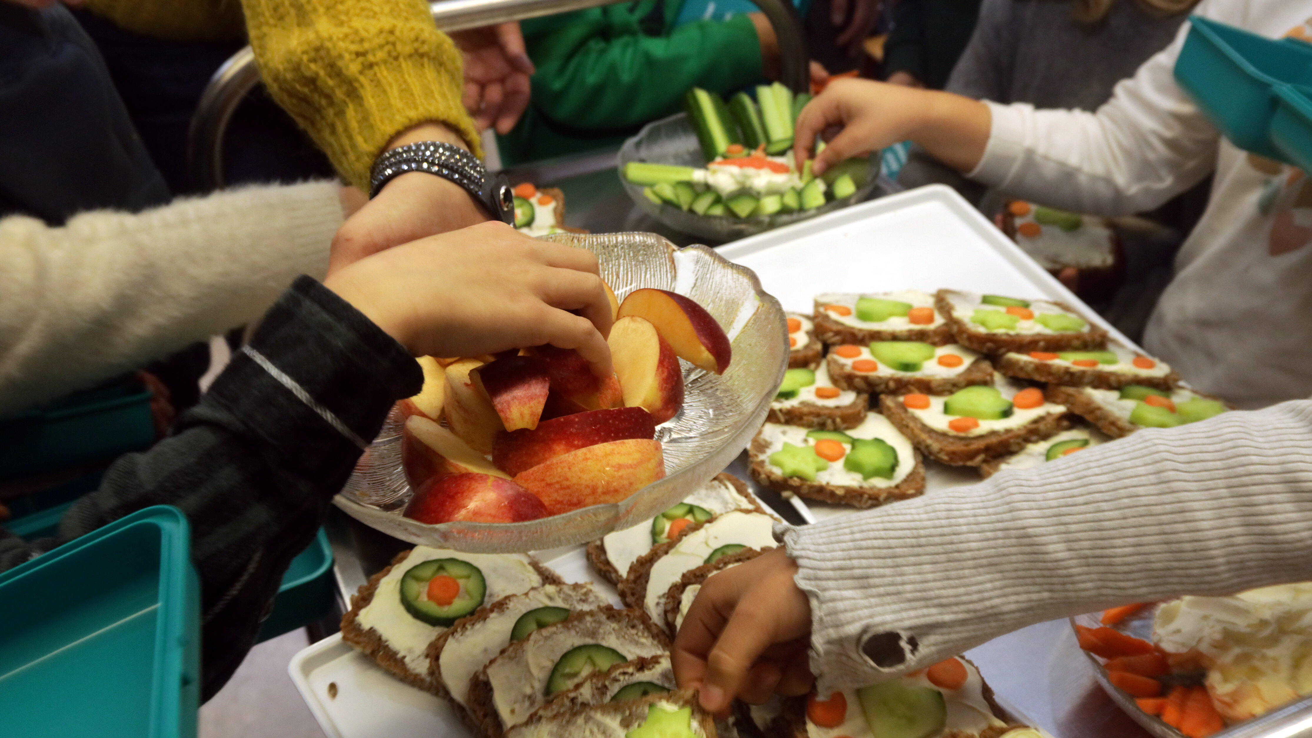 Hände von Kindern belegen Brote. Sie legen diese in Plastik-boxen