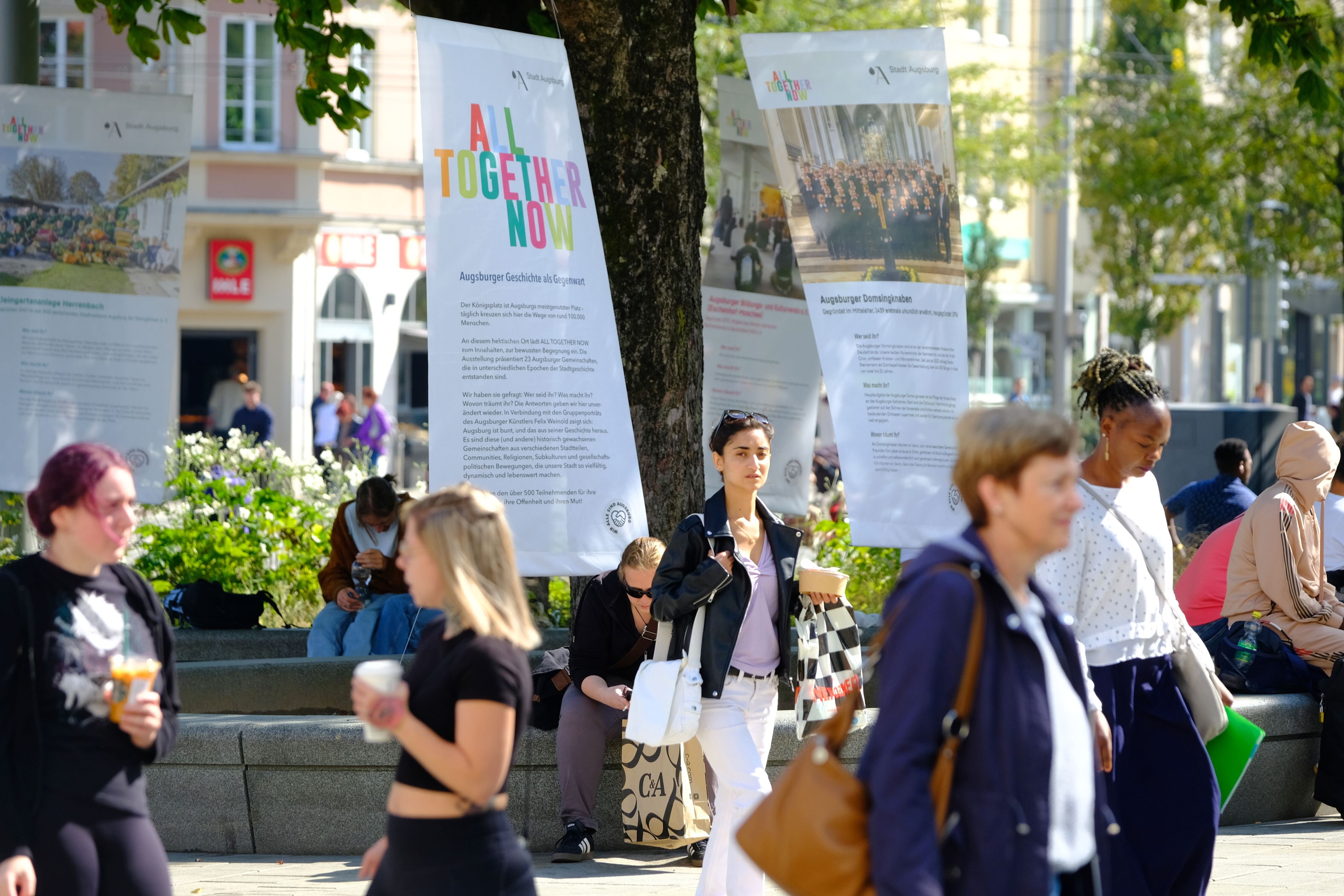 Am Königsplatz laufen Leute an bunten Plakaten vorbei