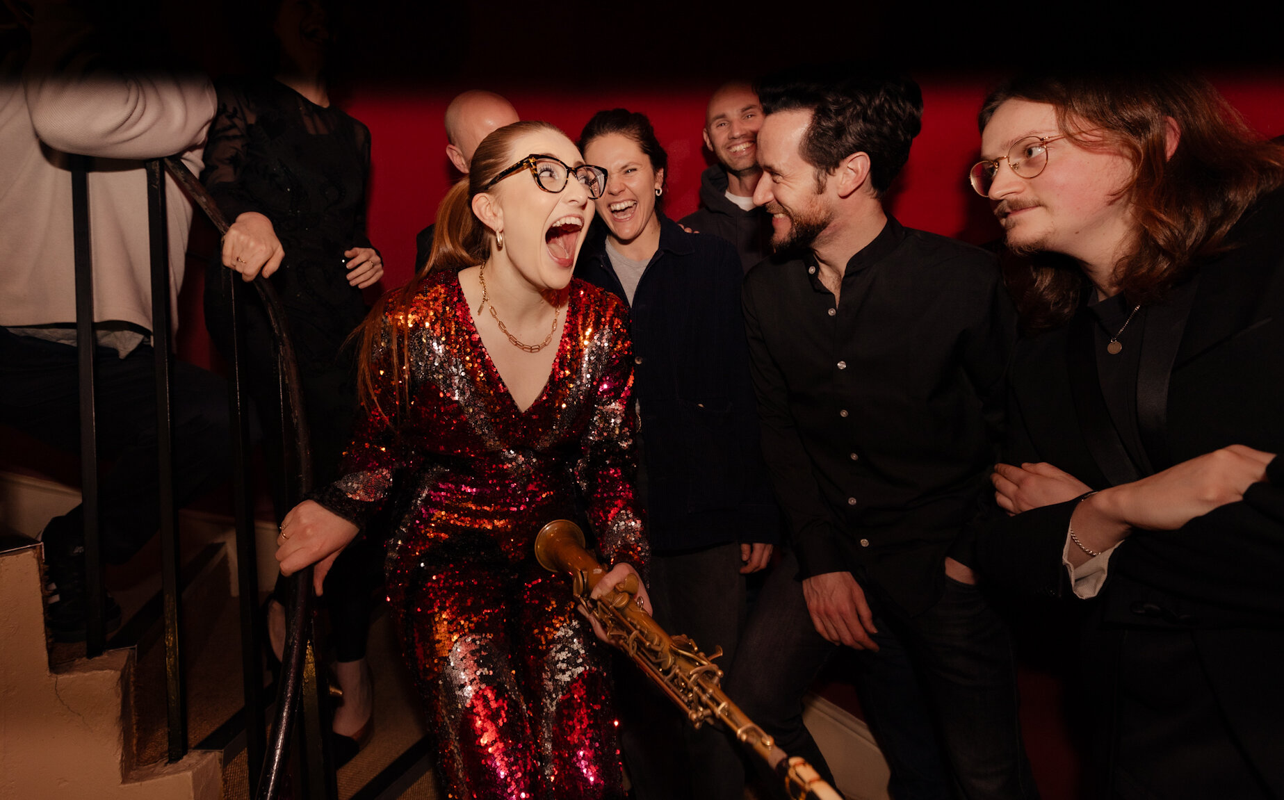 Frau im Glitzerkleid hat mit ihren Freunden unfassbar großen Spaß beim Musizieren