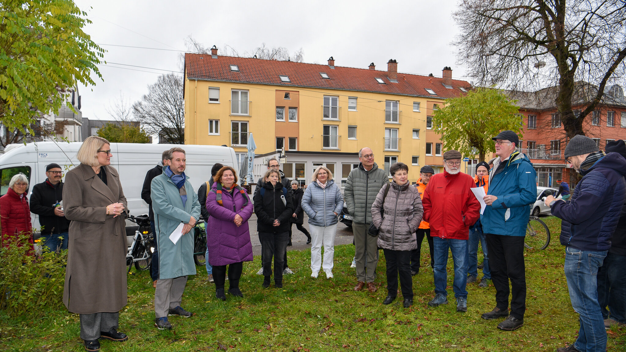 Viele Leute stehen auf einem Platz in einem Stadtteil