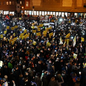 Auf dem Rathausplatz stehen mehrere Tausend Menschen bei Dunkelheit und halten Lichter in die Höhe