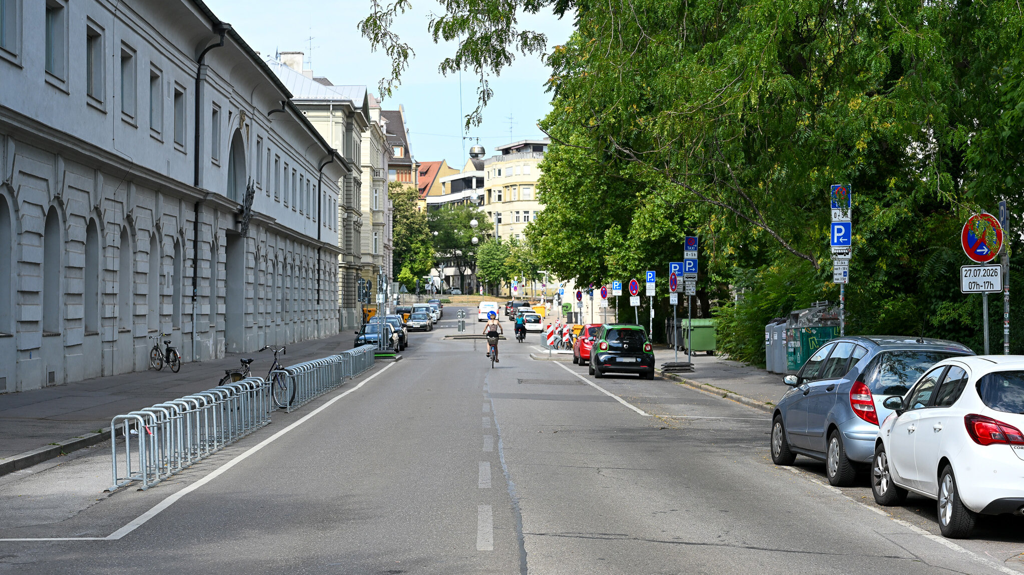 Eine Straße mit Parkplätzen und einem Schulgebäude