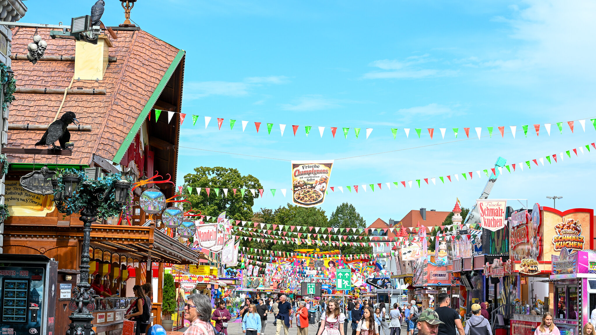 Reges Treiben beim Familientag auf dem Augsburger Plärrer. Menschen flanieren bei strahlend blauem Himmel über das Plärrergelände