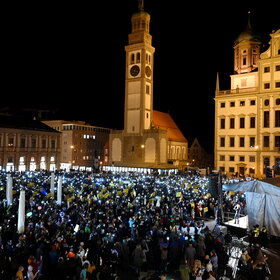 Auf dem Rathausplatz stehen mehrere Tausend Menschen bei Dunkelheit und halten Lichter in die Höhe