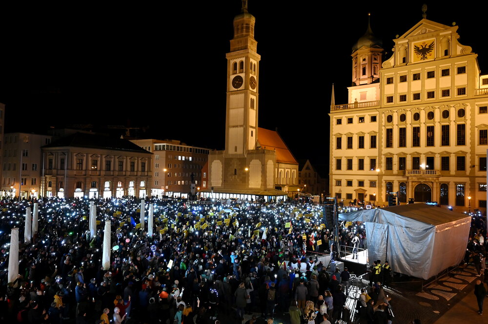 Auf dem Rathausplatz stehen mehrere Tausend Menschen bei Dunkelheit und halten Lichter in die Höhe