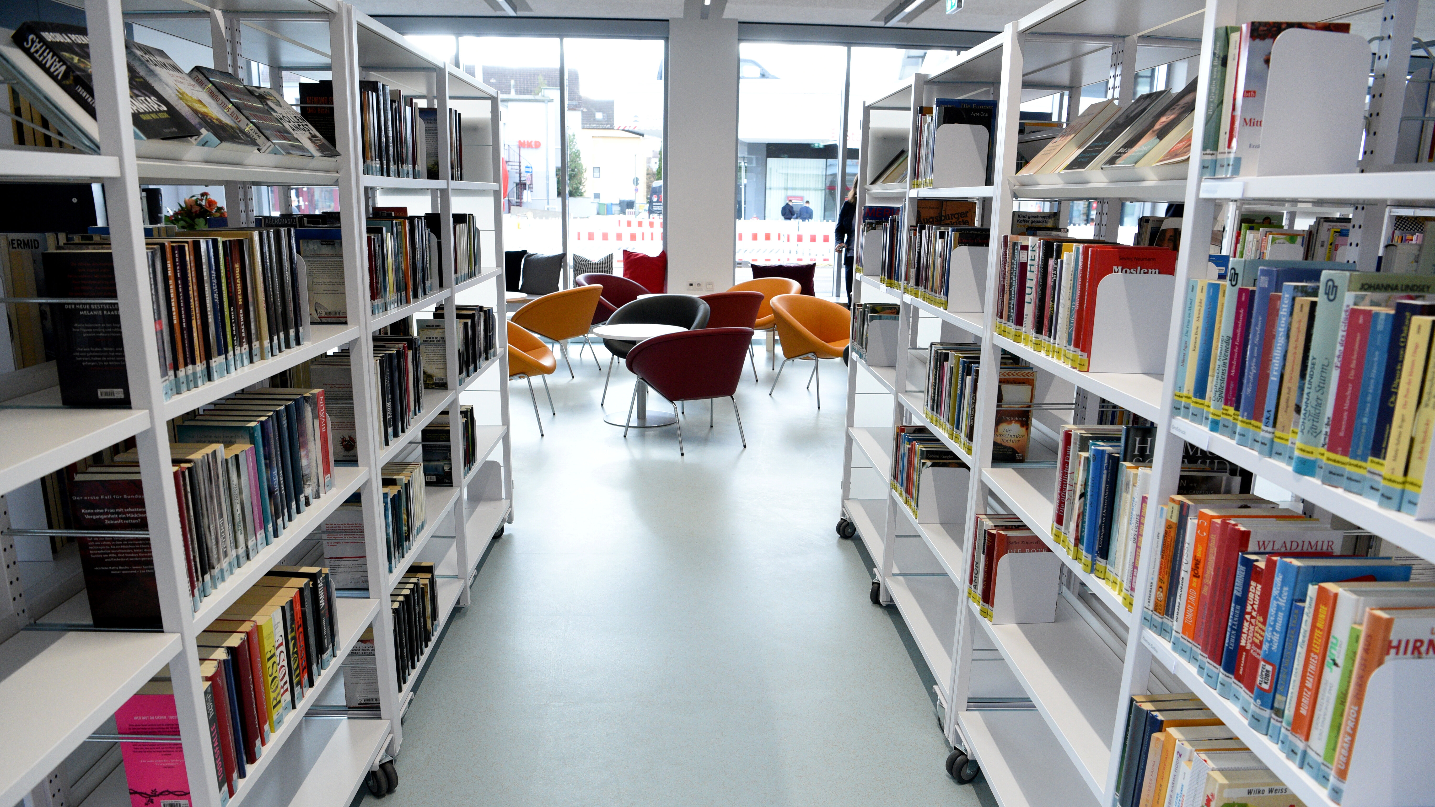 Ein Blick durch die Bücherregale in der Stadtbücherei Lechhausen zur gemütlichen Sitzgelegenheit