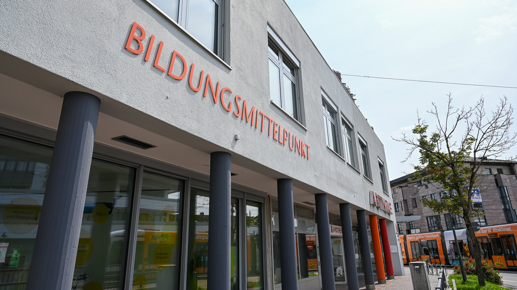 Das Foto zeigt ein weißes Gebäude. Darauf steht in großen orangenen Buchstaben Bildunsgmittelpunkt