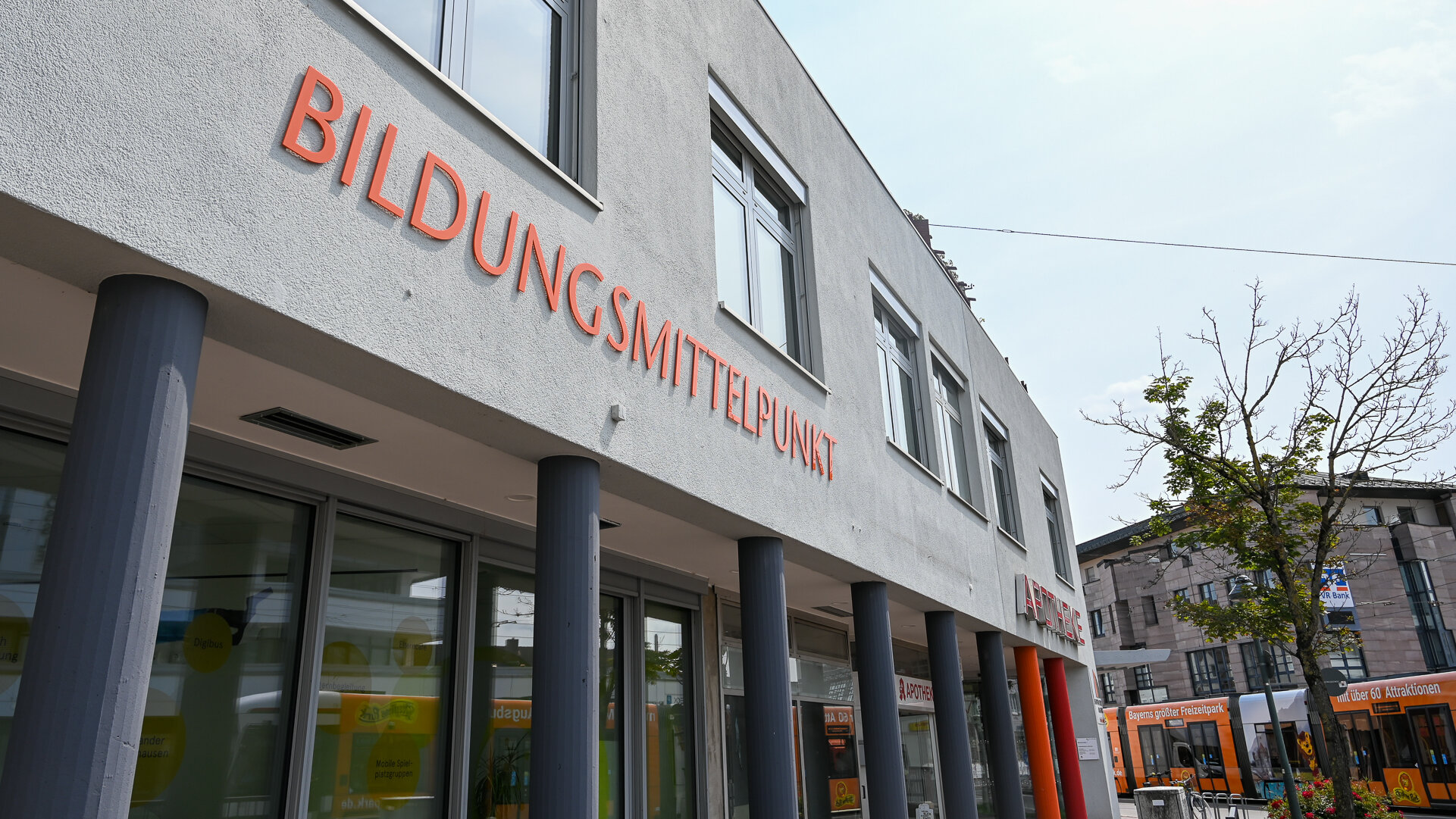 Das Foto zeigt ein Gebäude mit weißer Fassade, auf dem in großen orangenen Buchstaben Bildungsmittelpunkt steht
