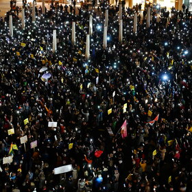 Auf dem Rathausplatz stehen mehrere Tausend Menschen bei Dunkelheit und halten Lichter in die Höhe