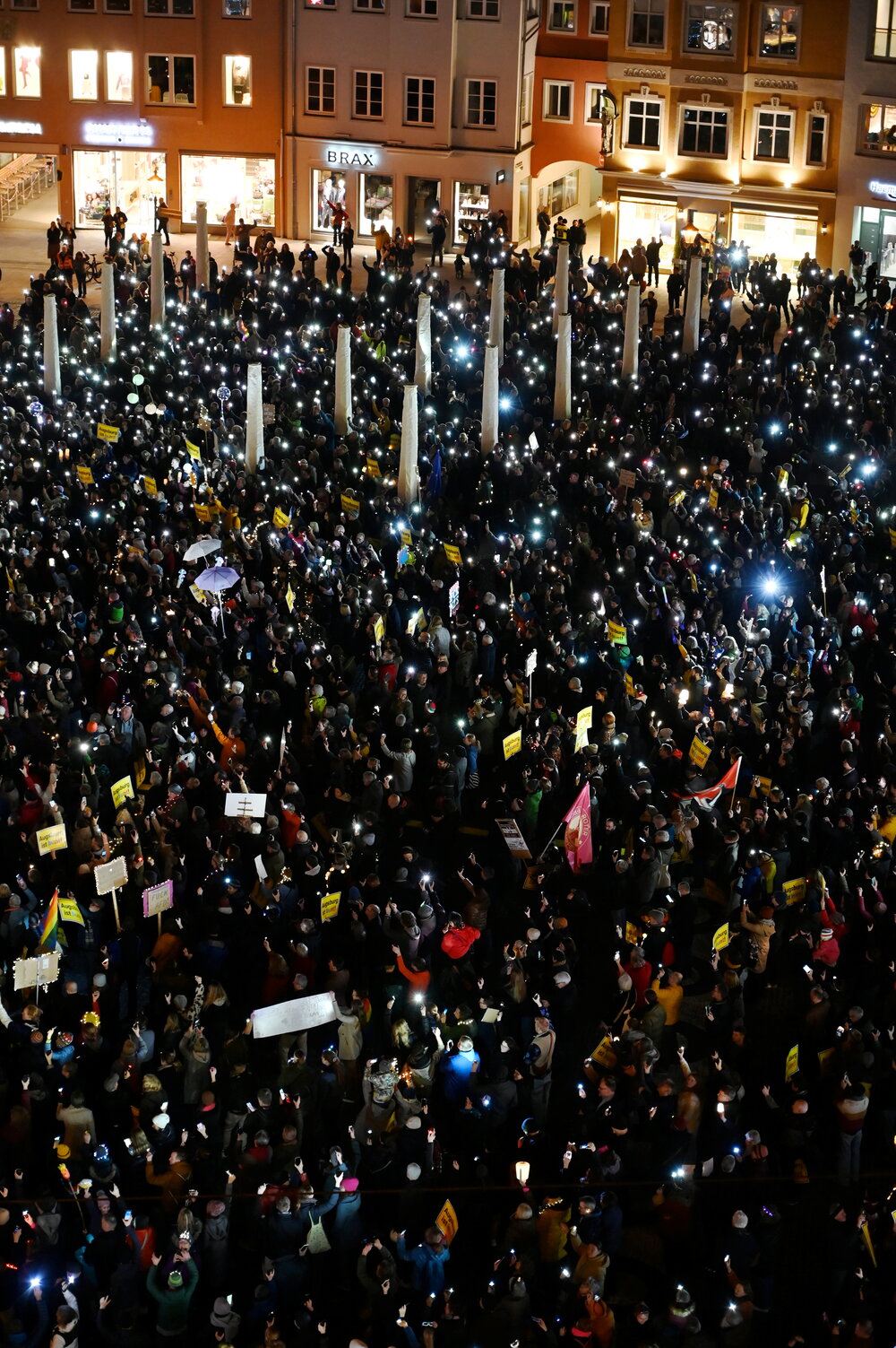 Auf dem Rathausplatz stehen mehrere Tausend Menschen bei Dunkelheit und halten Lichter in die Höhe