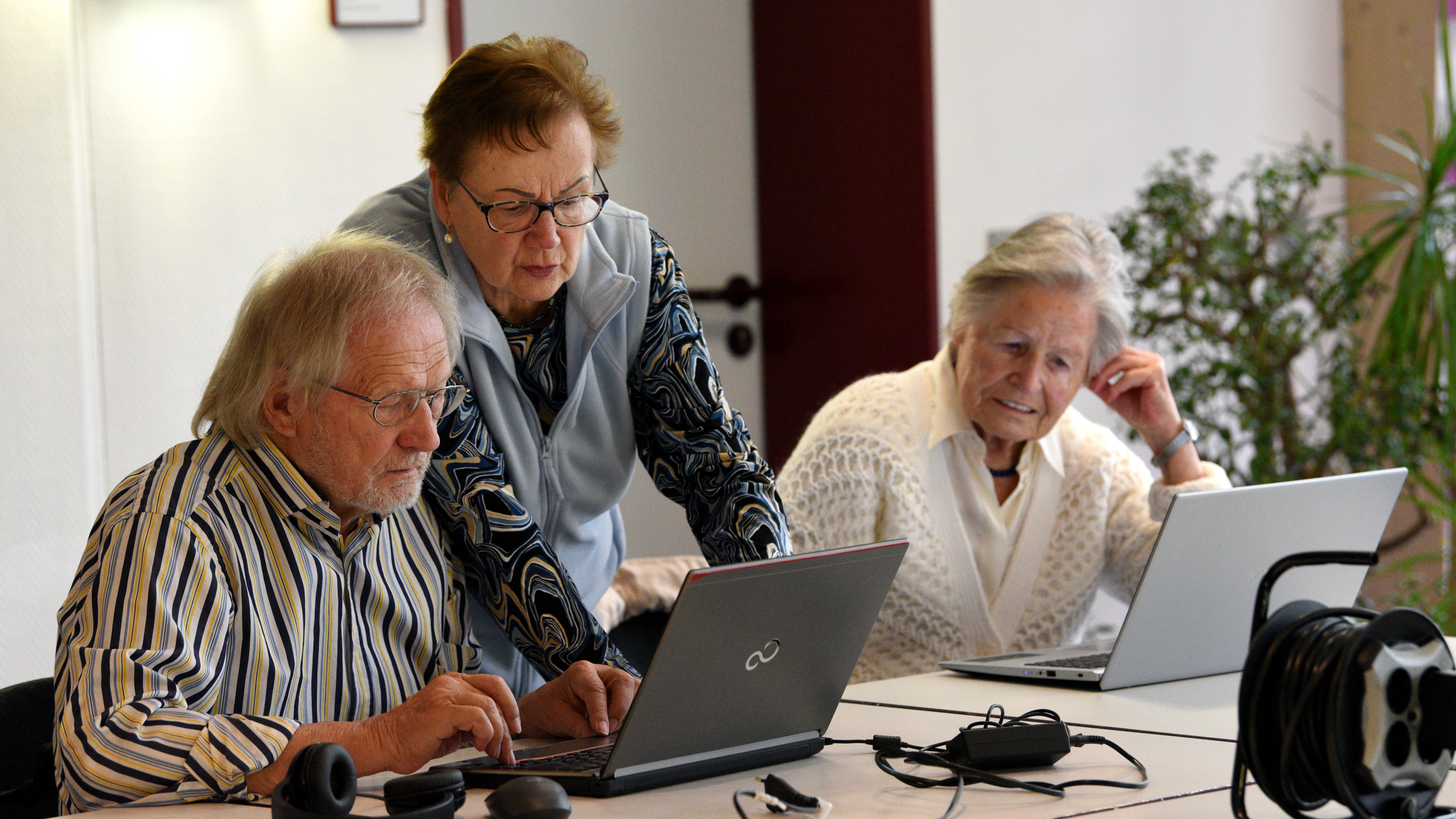 drei ältere Menschen am Computer, eine davon erklärt etwas