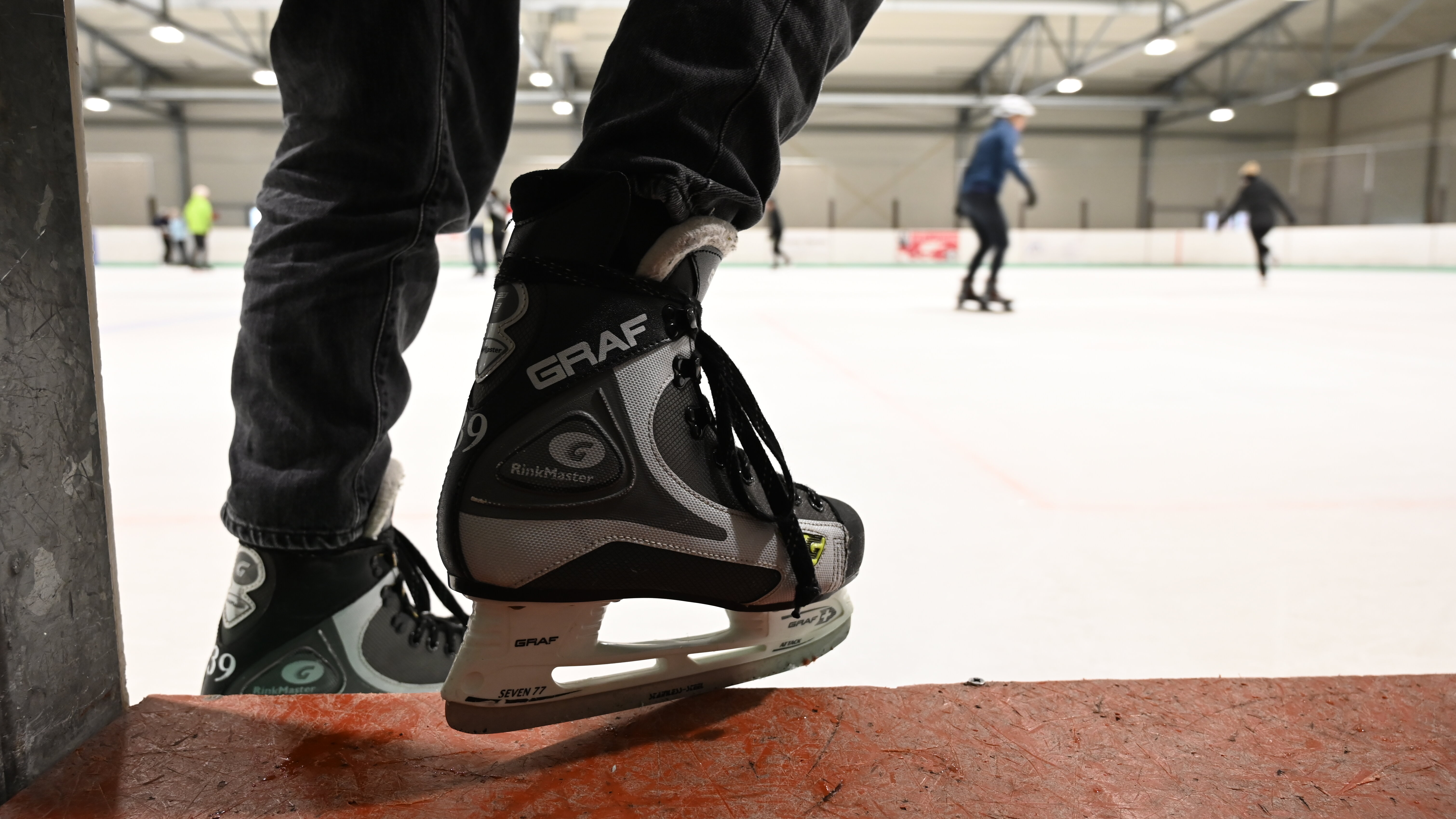 Ein Mensch mit Schlittschuhen betritt eine Eisfläche