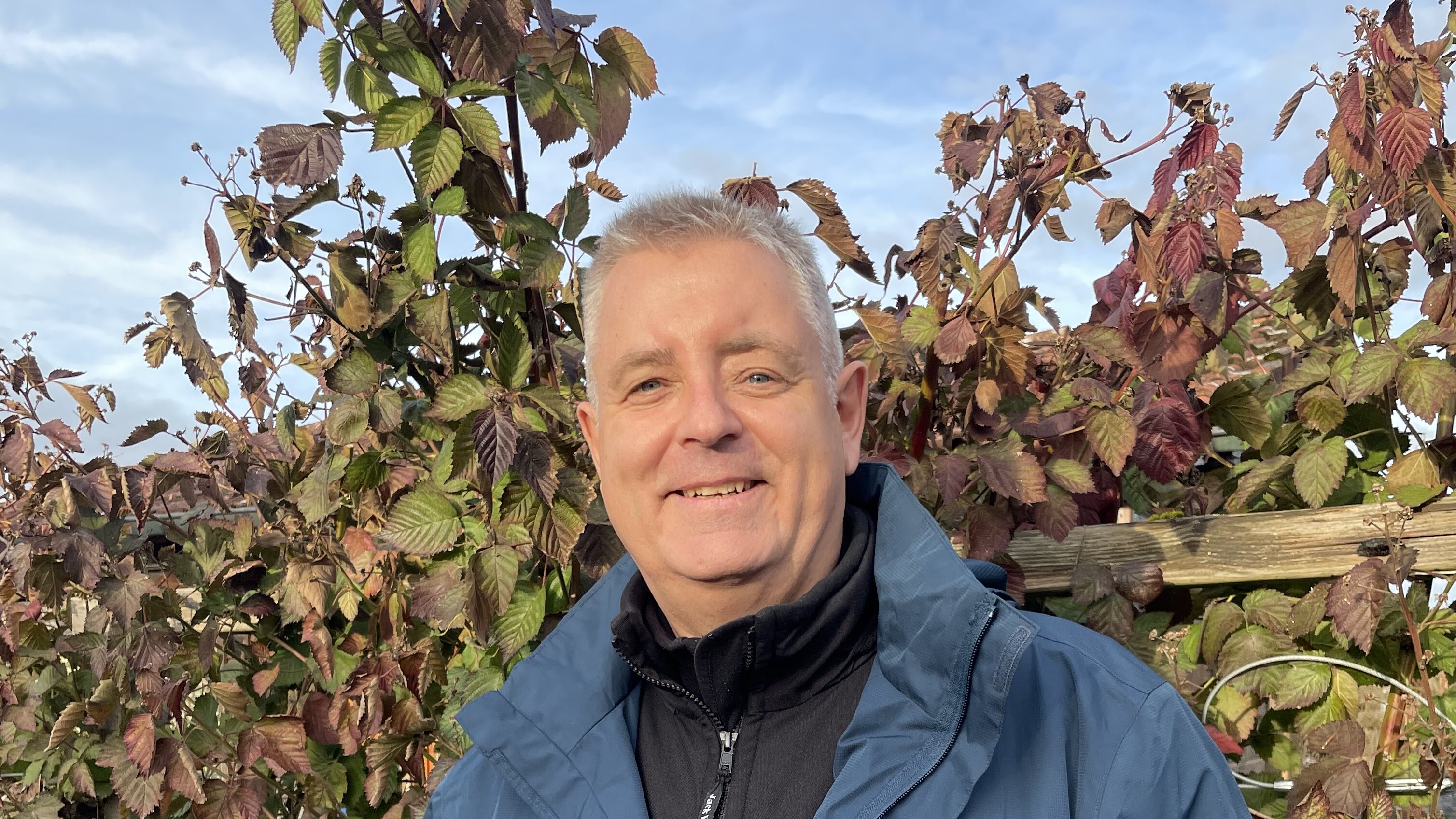 ein älterer Mann hält lächelnd ein Wespennest in beiden Händen