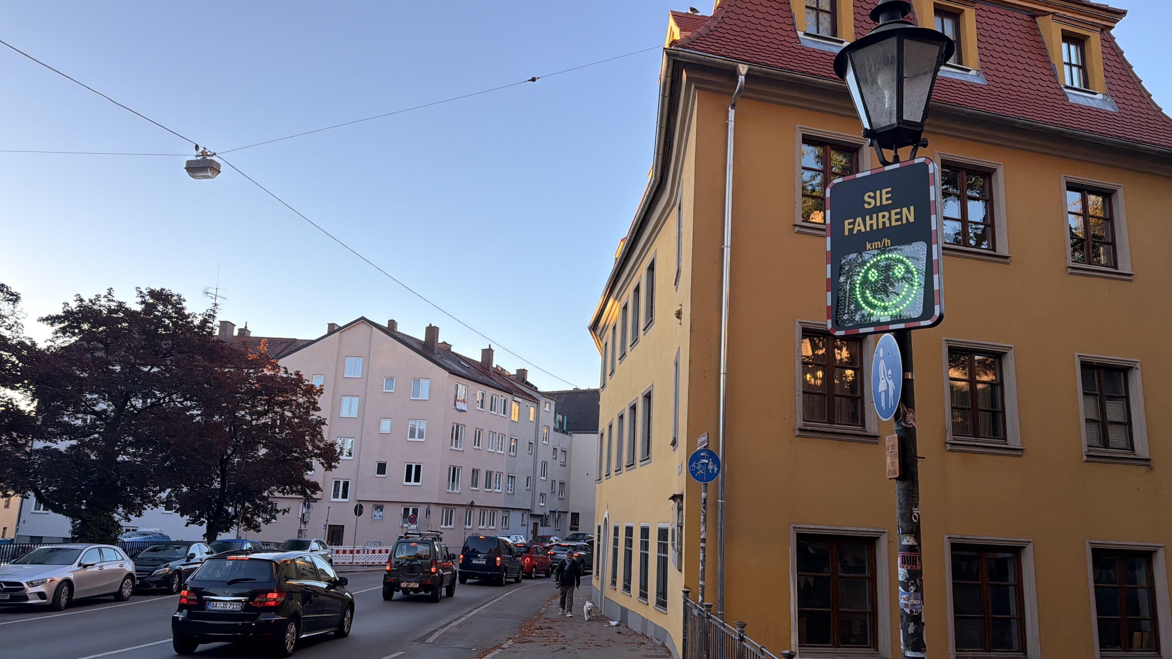 An einer Straße steht eine digitale Anzeige, die ein grünes lächelndes Gesicht zeigt