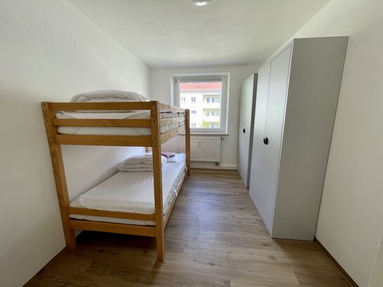 weiß gestrichenes Zimmer mit Stockbett und Kleiderschrank
