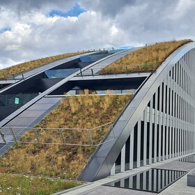 Das Dach am Innovationspark ist geformt wie ein Halbkreis. Dieser Halbkreis ist zum Teil von Grasflächen bedeckt.