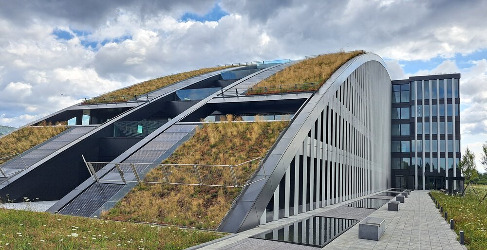 Das Dach am Innovationspark ist geformt wie ein Halbkreis. Dieser Halbkreis ist zum Teil von Grasflächen bedeckt.