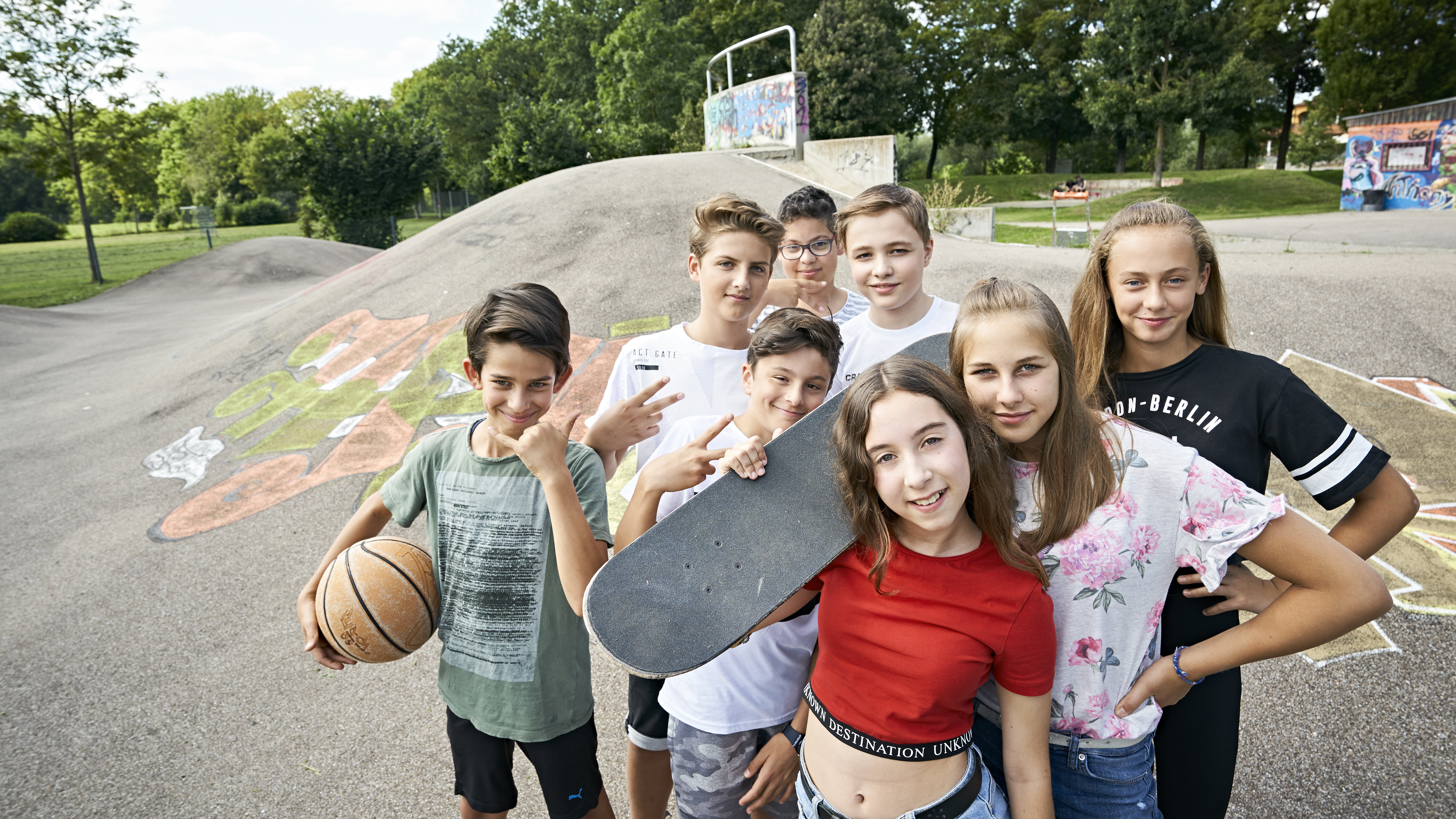 Kinder auf einem Skaterplatz, alle sehen in die Kamera