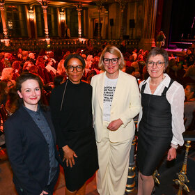 Das Foto zeigt vier festlich gekleidete Frauen, im Hintergrund das Parktheater