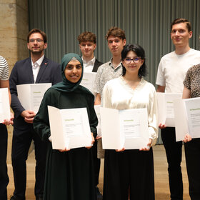 Das Foto zeigt die sieben Preisträgerinnen. In der vorderen Reihe stehen drei junge Frauen, in der hinteren vier junge Männer. Sie halten alle eine Urkunde in den Händen und lächeln in die Kamera