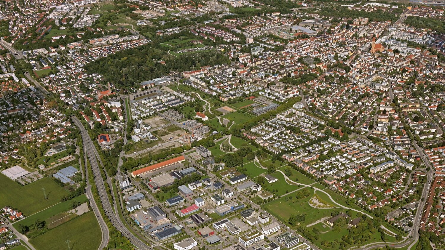 Aus einem Flugzeug fotografiert sieht man Wohnhäuser und einen großen Park mit vielen Wegen