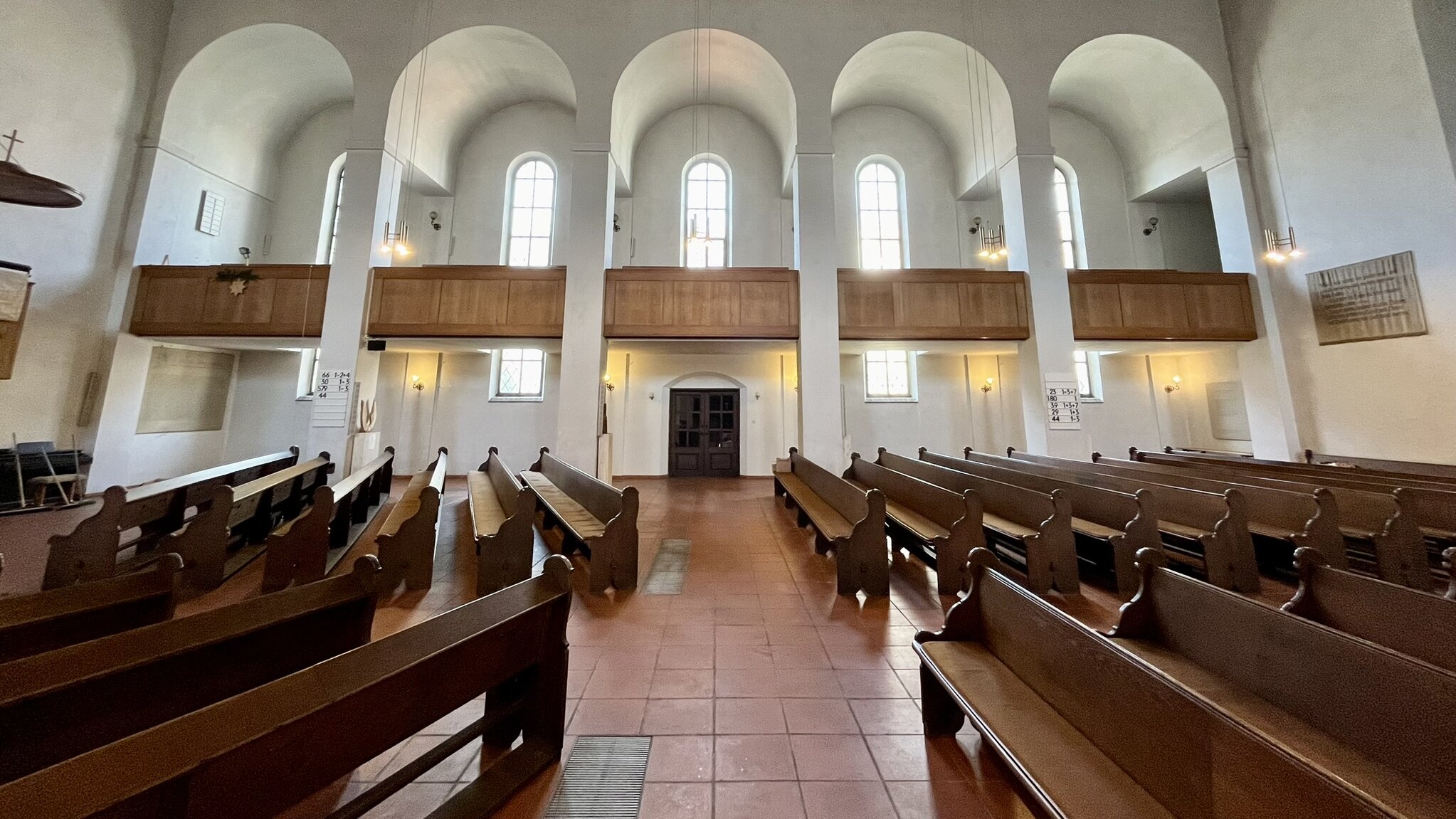 Kirchenraum mit hohen BogenFenstern, in dem Kirchenbänke aufgestellt sind