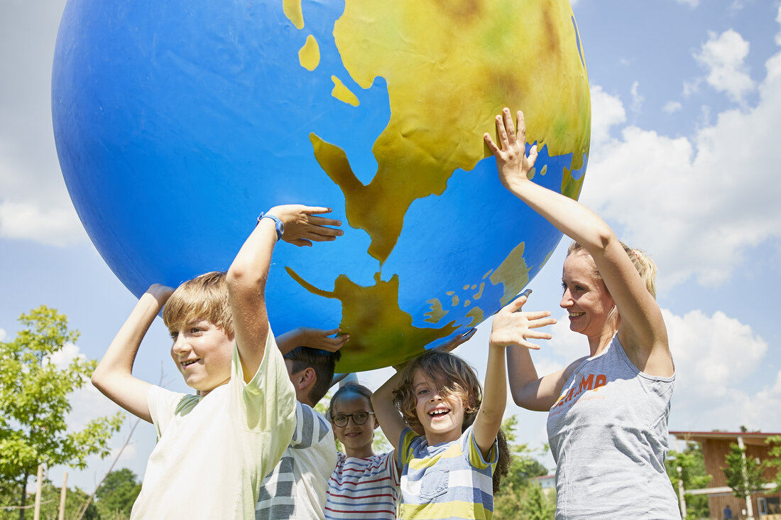 4 Kinder halten eine aufblasbare Weltkugel über ihren Köpfen