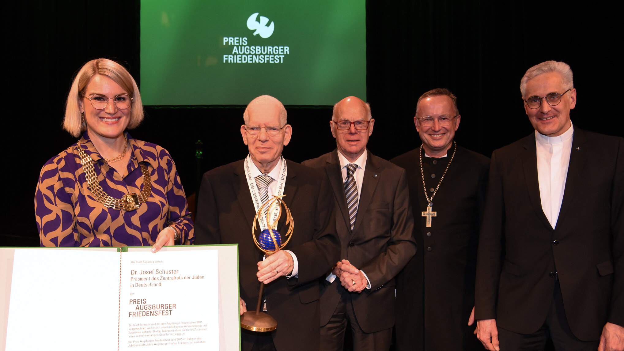 Eine Frau und vier Männer in festlicher Kleidung. Die Frau hält eine Urkunde in der Hand
