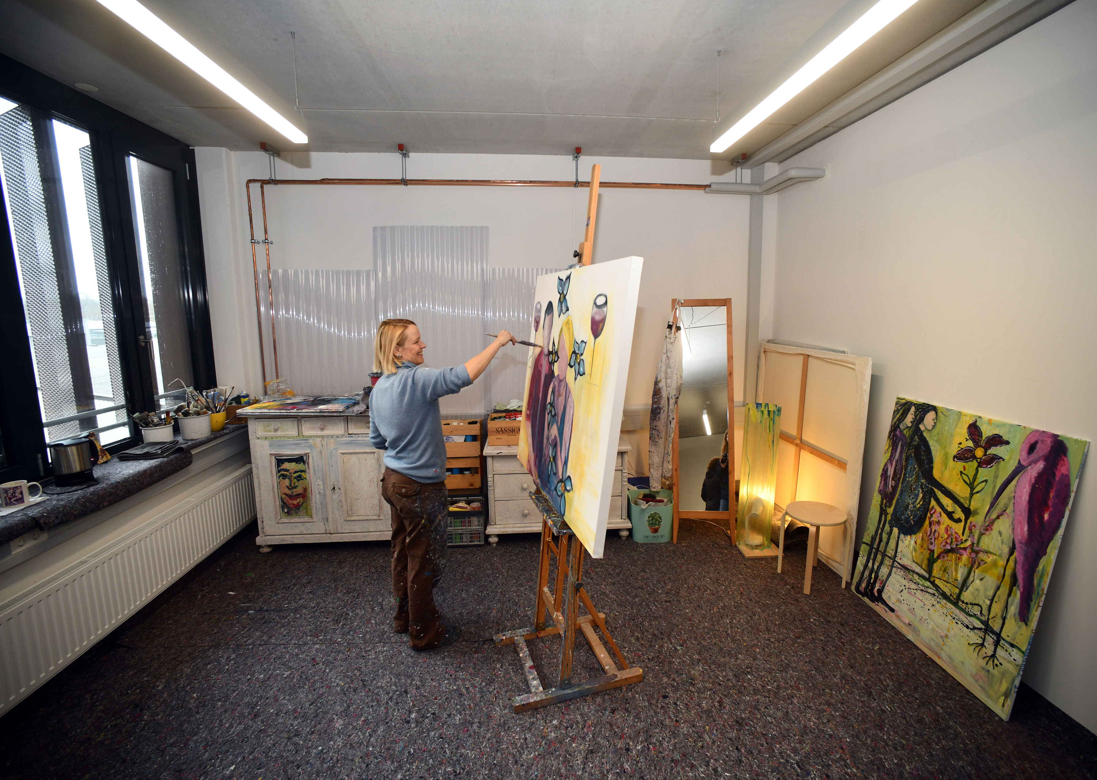 Man sieht eine Künstlerin beim Malen in ihrem Atelier.