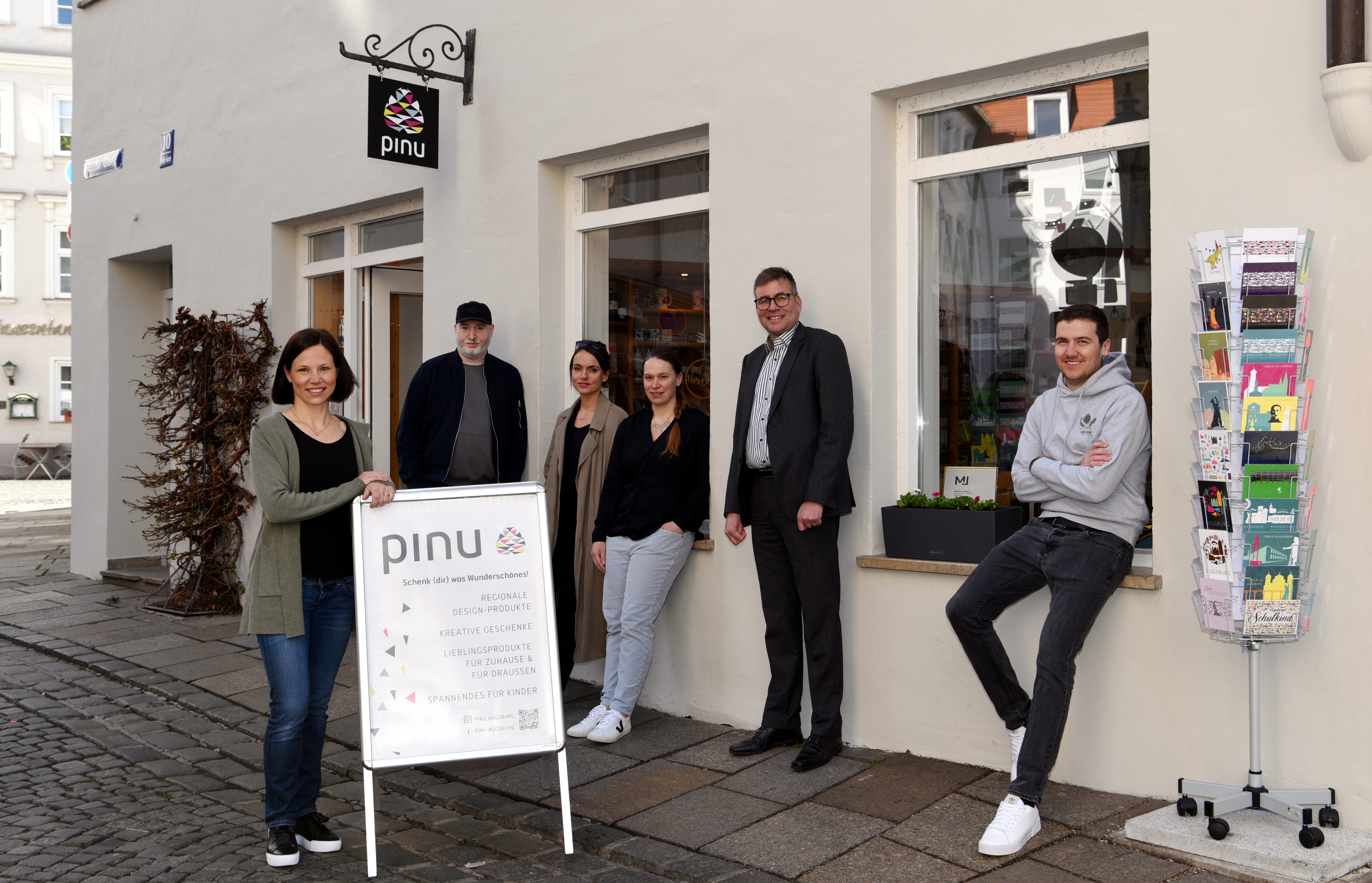 Sechs Menschen stehen vor einem Geschäft in der Augsburger Altstadt