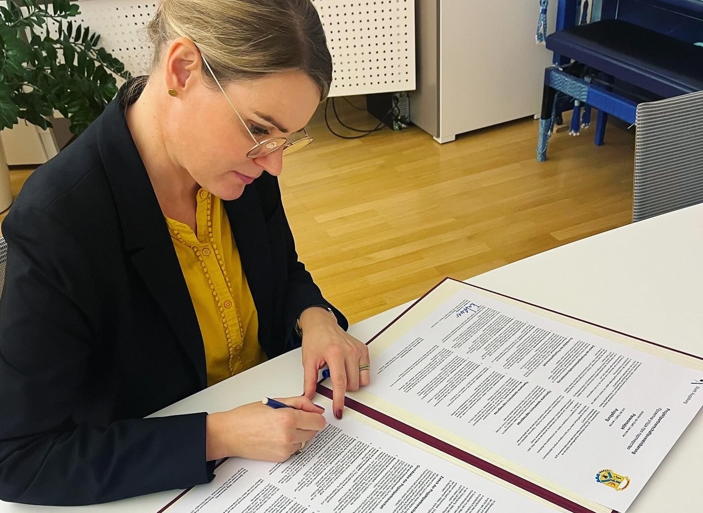 Oberbürgermeisterin Eva Weber sitzt an ihrem Schreibtisch. Vor ihr liegt ein zweiseitiges Dokument, das sie gerade unterschreibt.