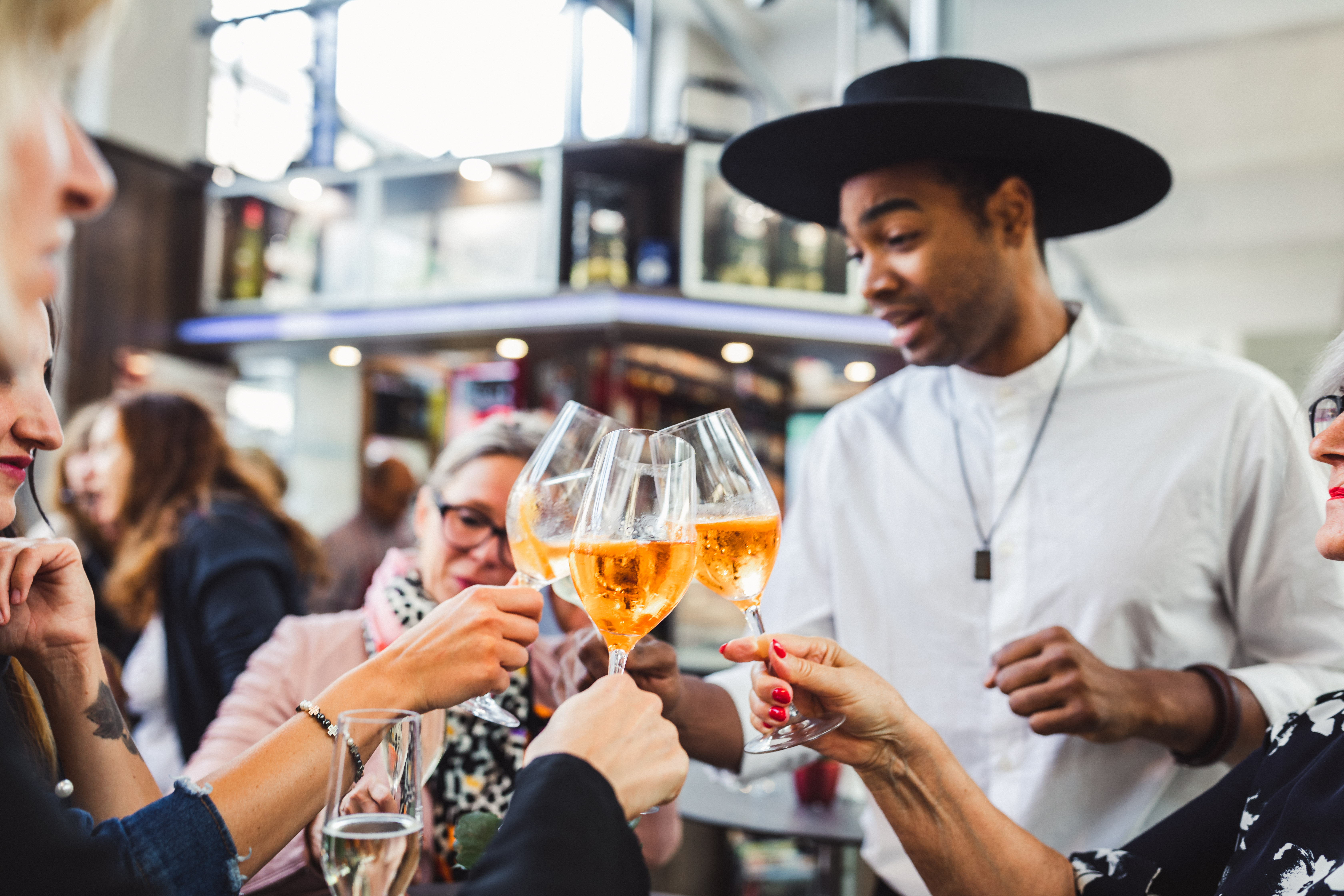 Ein Mann teilt Gläser Aperol Spritz an Gäste aus. 