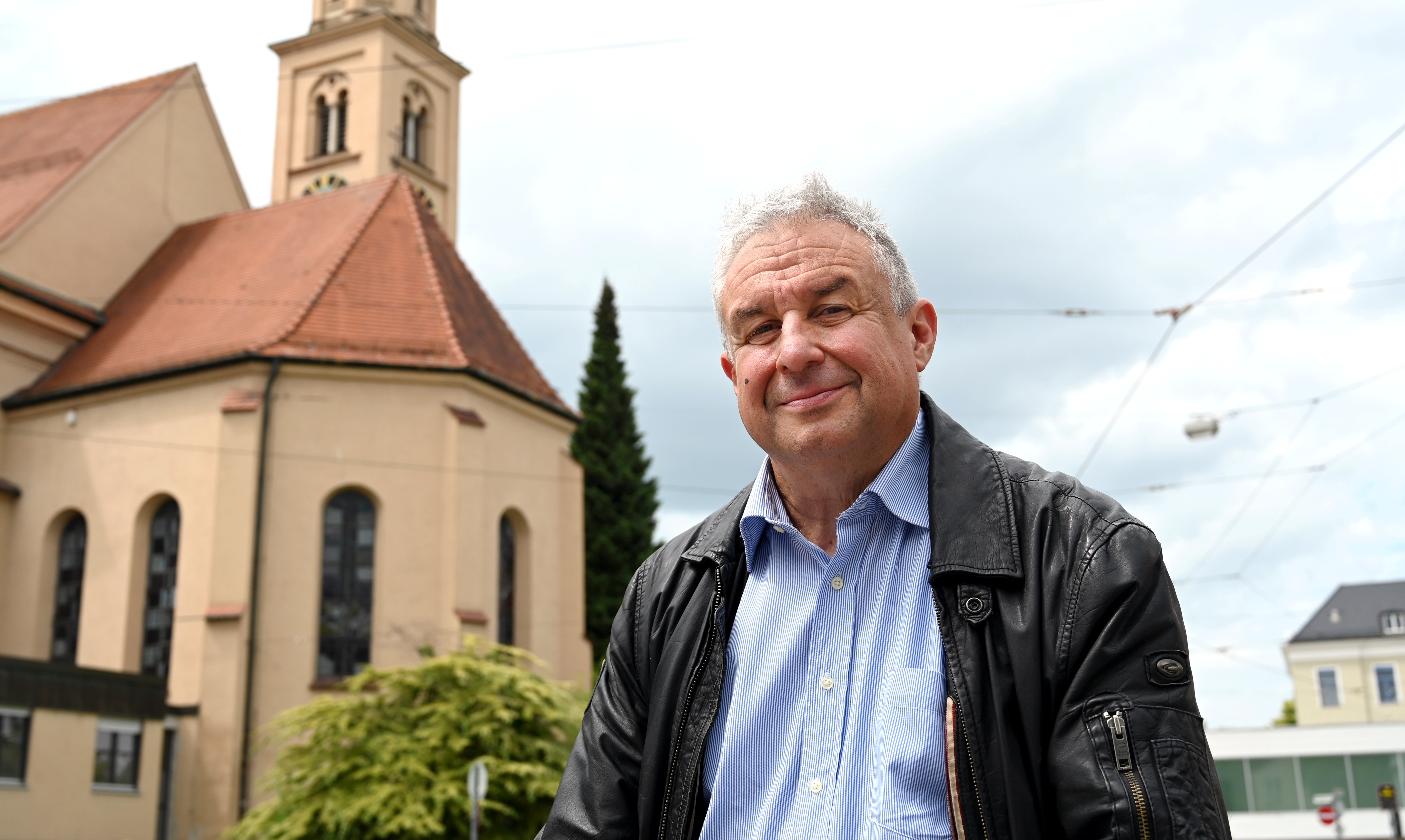 Ein etwa 50-jähriger Mann steht vor einer Kirche.