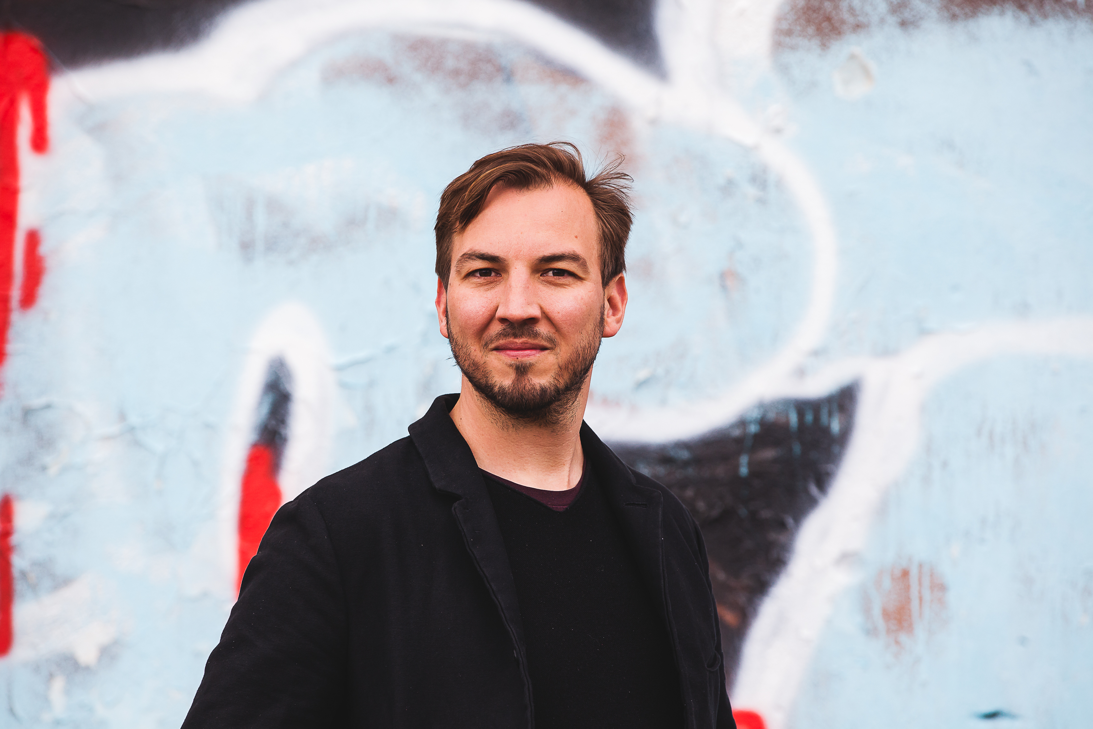 Ein junger Mann steht vor eine Graffiti-Wand