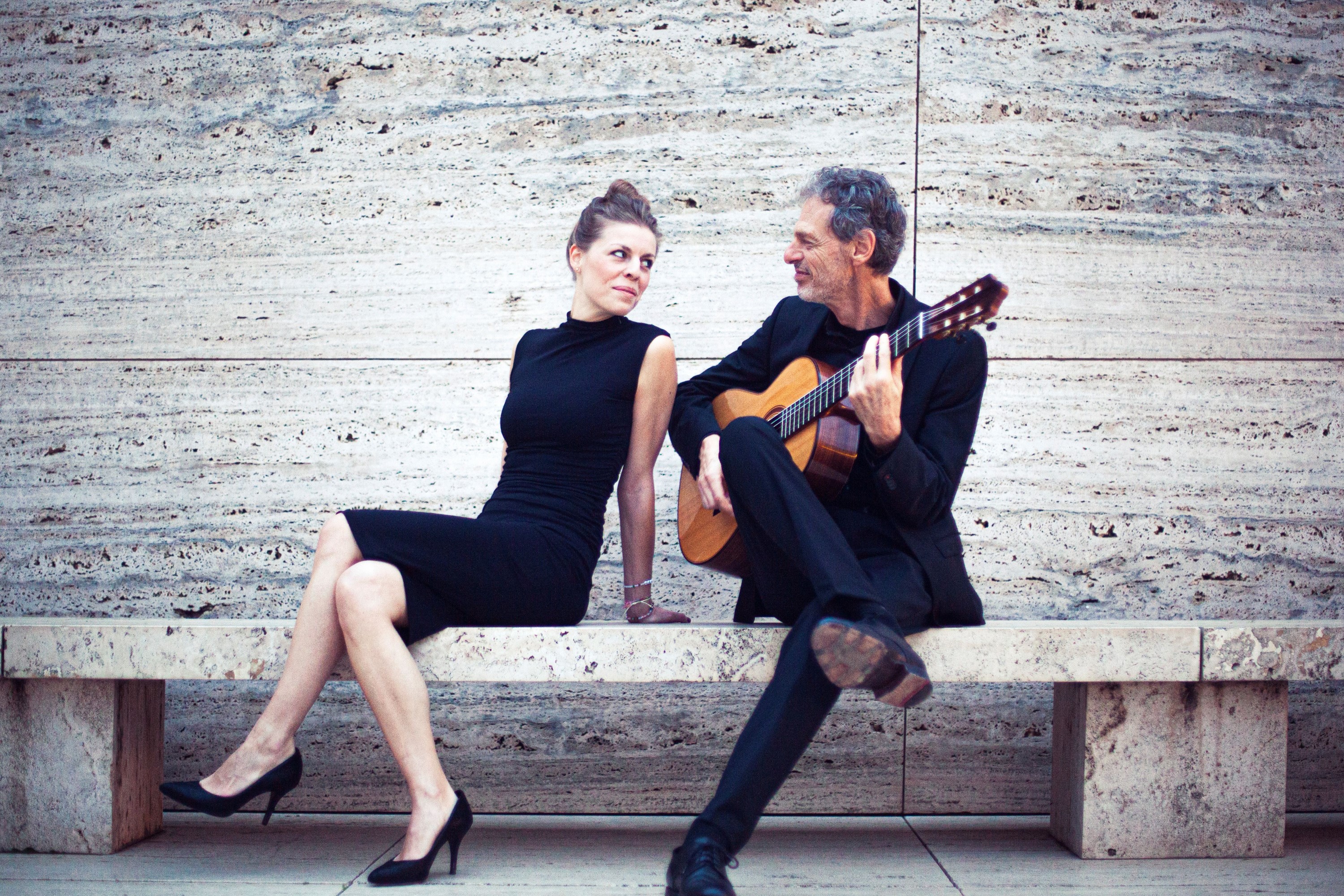 Das Duo Gruber - Vater und Tochter - sitzen auf einer Bank und singen und spielen Songs von Kurt Weil