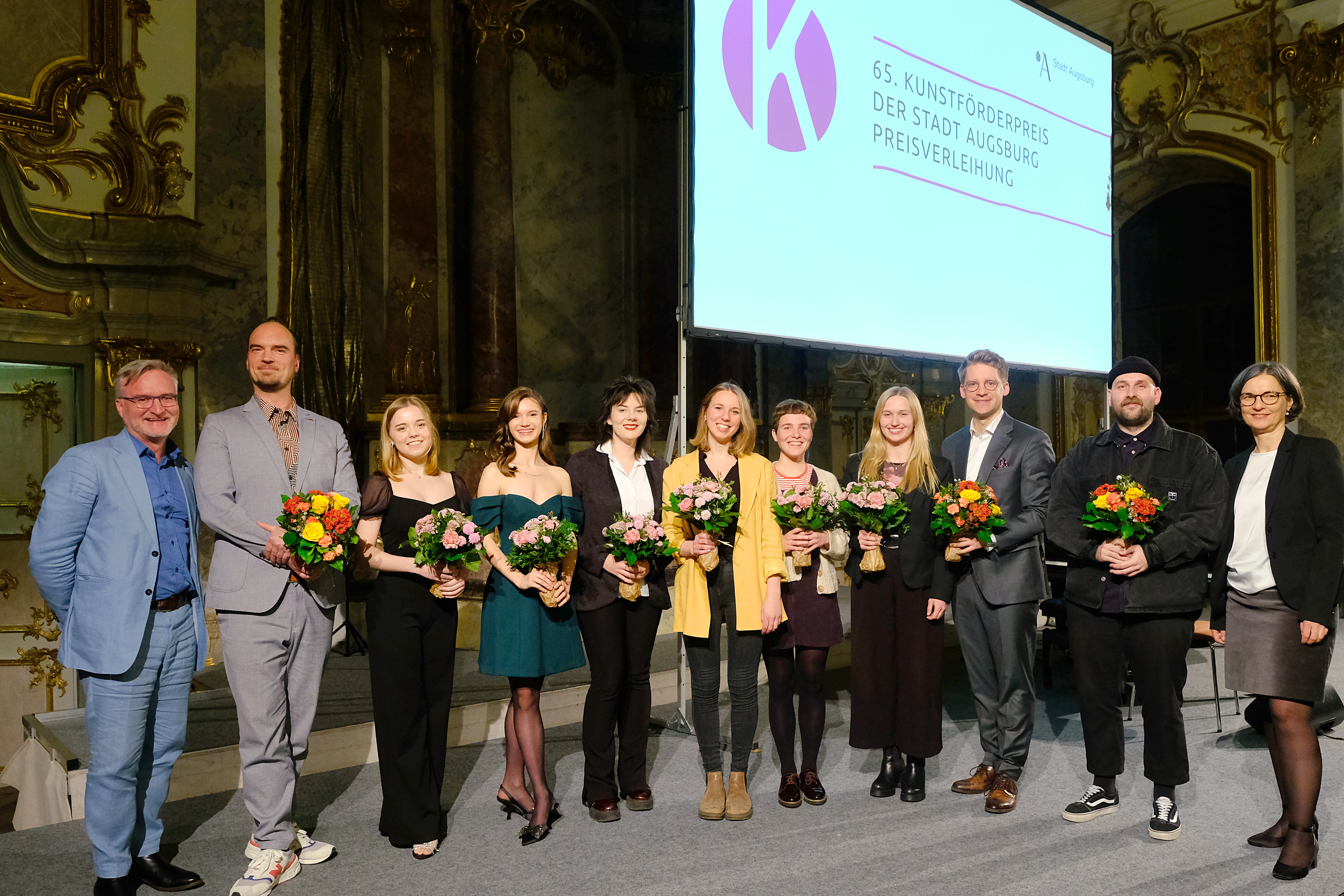 Zehn Menschen stehen in einem schönen Saal