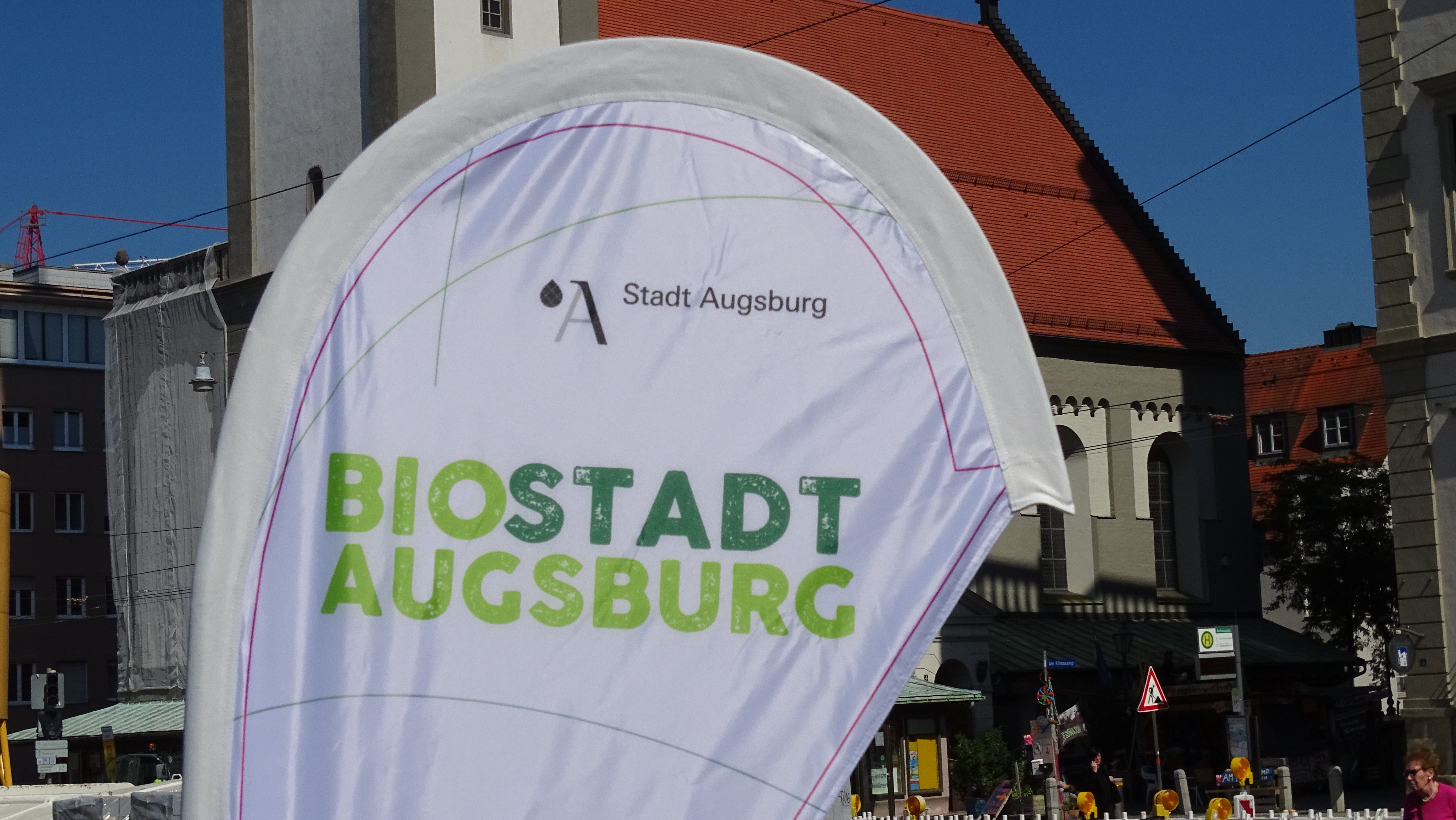 Eine Fahne mit der Aufschrift Biostadt Augsburg steht vor dem Perlachturm